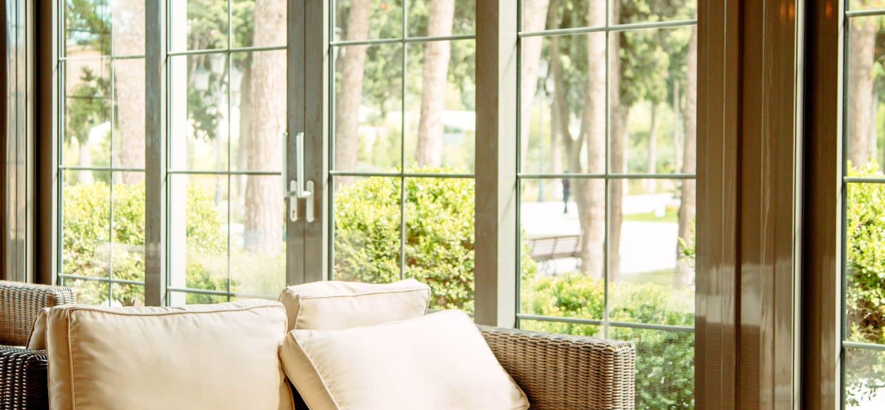 Wicker sofa by glass doors in sunroom.